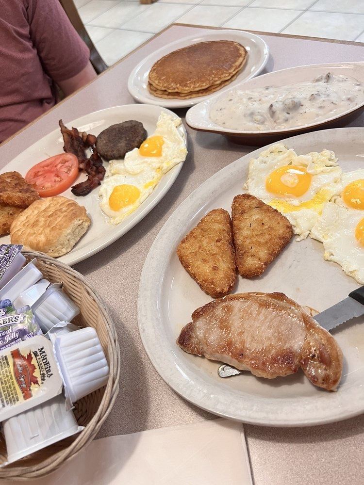 A big country breakfast with eggs, hash browns and a pork chop