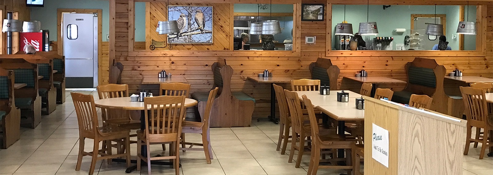 The dining room at Cook's: knotty pine walls, green booths and bucket lamps